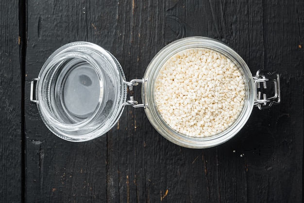 Sesame seeds set, in glass jar, on black wooden