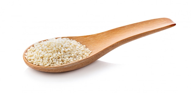 Sesame seeds in a wooden spoon on white wall