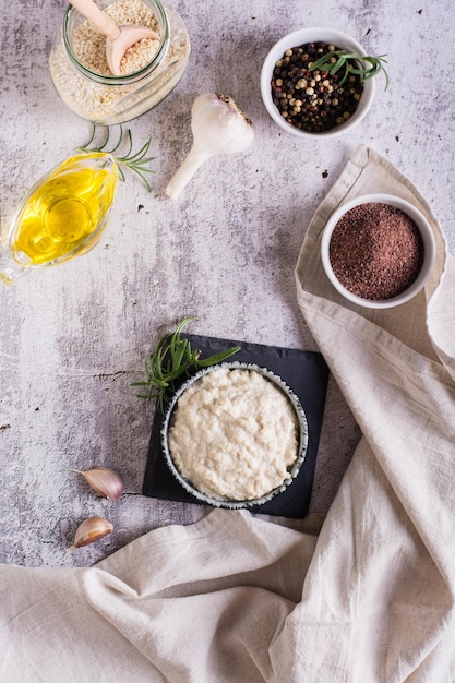 Sesame tahini with black salt in a bowl and cooking ingredients on the table Top and vertical view