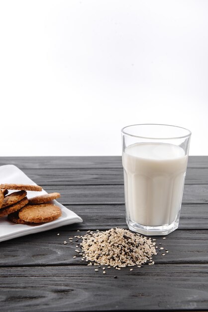 Sesamzaadmelk in een glas witte sesamzaadjes op tafel rauwe voeding het alternatief voor melk