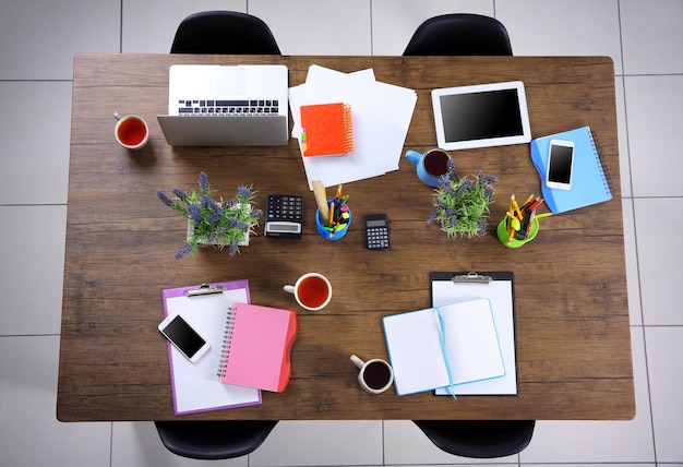 Session concept Table with tablet laptop papers and cups of tea Top view