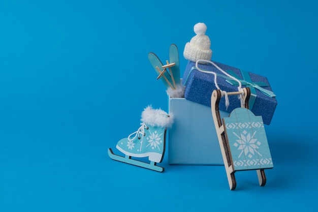 A set of accessories for winter recreation and sports and a\
gift box on a blue background. accessories for winter sports and\
recreation.