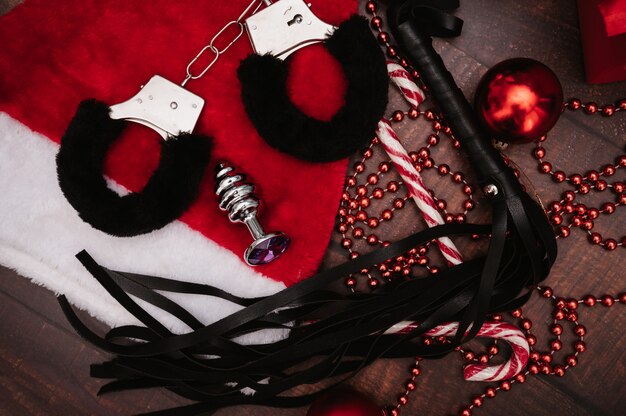 A set of adult BDSM toys with Christmas decor. Flatley. Handcuffs, whip, anal plug, Christmas balls.