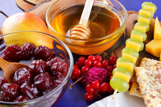 Set or assortment of cheeses closeup Different kinds of cheeses with nuts berries fruits cherry jam and honey on a blue background