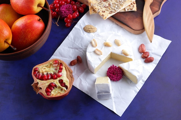 Set or assortment of cheeses closeup Different kinds of cheeses with nuts berries fruits and honey on a blue background