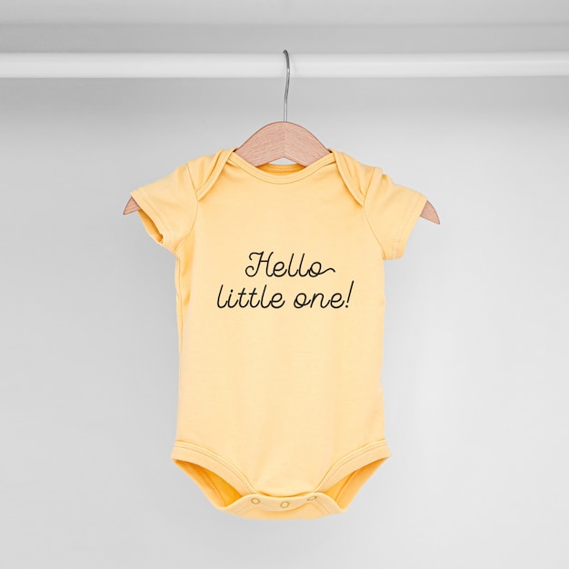 Set of baby bodysuits for a newborn girl and boy on hangers in white wardrobe. Motherhood, cleaning home kids wardrobe. Minimal fashion concept.