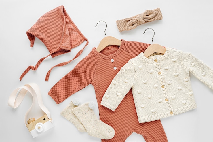 Photo set of  baby rompers, hat,  hairband and  knitted jumper on white bed. fashion  baby clothes and accessories. flat lay, top view