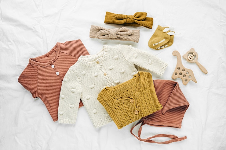 Photo set of  baby rompers, hat,  hairband and  knitted jumper on white bed. fashion  baby clothes and accessories. flat lay, top view