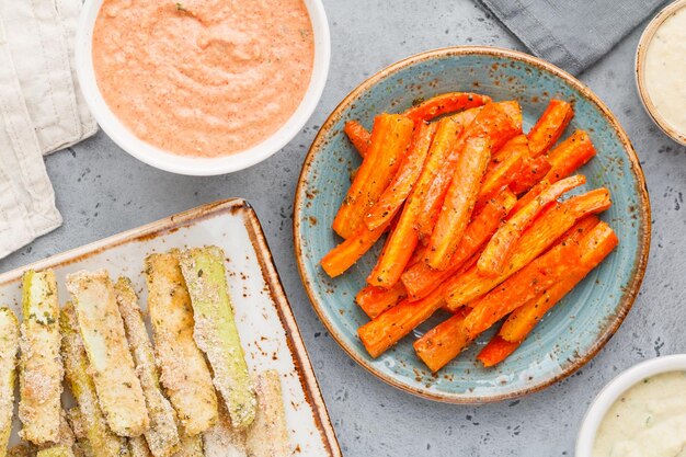 Set of baked season vegetable sticks of zucchini and carrots with sauce and hummus Vegetarian healthy food Flat lay top view