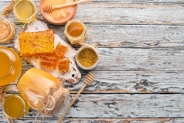 Set of bee products and honey on a white wooden background. Free space for text. Top view.