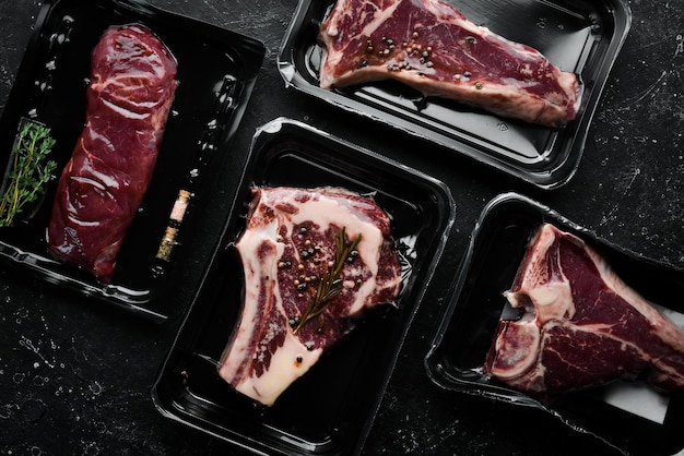 Set of beef steak in vacuum packing market top view flat lay\
top view on black stone cutting table