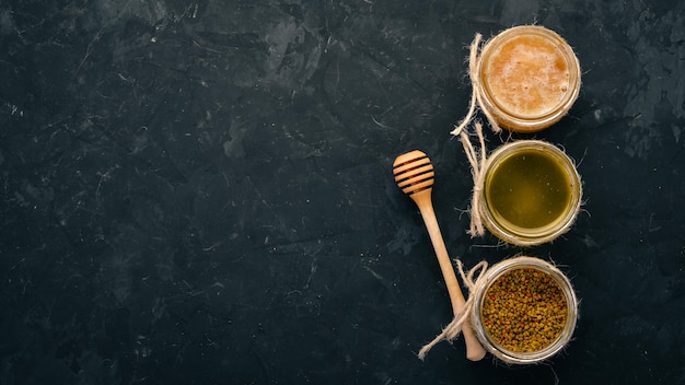 A set of beekeeping products and honey on a black stone background Free space for text Top view