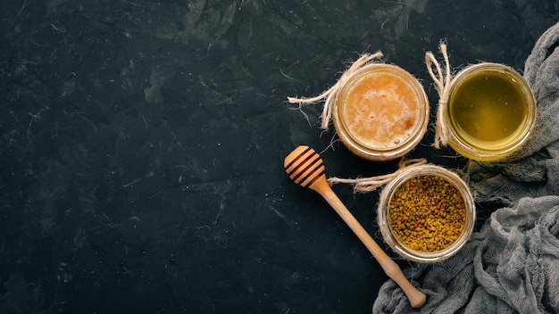 A set of beekeeping products and honey on a black stone background Free space for text Top view