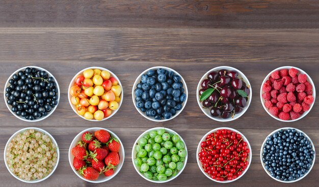 A set of berries in the round plates. Brown wooden background. Copy space.