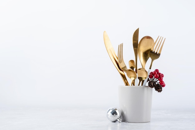 Set bestek van lepels, messen en vorken in beker met decoraties voor de feestdagen op de kopieerruimte van de eettafel