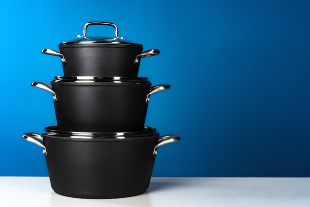 Set of black cookware against blue background