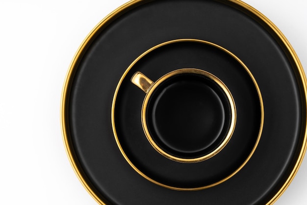 A set of black and golden ceramic plates and cup on a white background Top view