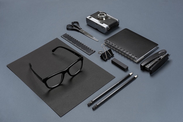 A set of black office accessories, glasses and old camera on gray background. Flat lay. Still life. Mock-up