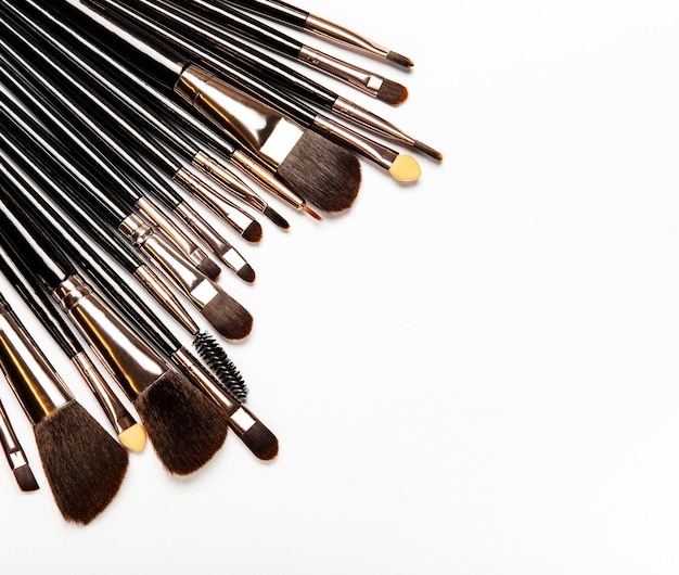Photo set of black professional makeup brushes with black handles on white background top view flat lay