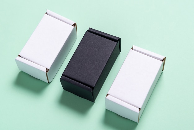 Photo set of black and white carton boxes on light green table, top view, flat lay