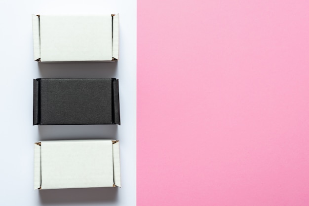 Set of black and white carton boxes on pink table, top view, copy space