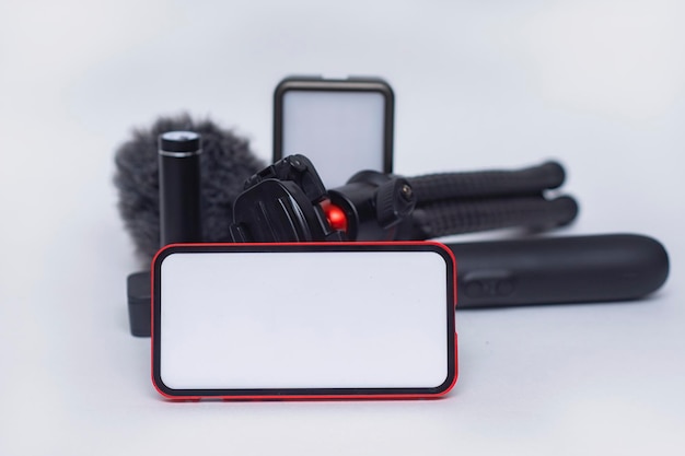 Set di gadget per blog mockup di smartphone con schermo bianco con power bank per treppiede con action camera e stabilizzatore con microfono su sfondo bianco