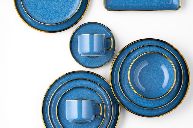 Un set di piatti in ceramica blu e tazza su sfondo bianco vista dall'alto