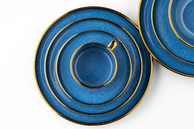 Un set di piatti in ceramica blu e tazza su sfondo bianco vista dall'alto