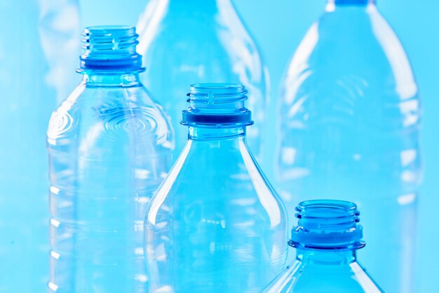 Set bottles of mineral water different types and sizes stand isolated on blue background. Plastic production and processing concept