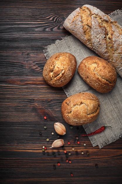 A set of bread, pepper, garlic on a brown wooden board