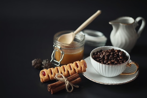 朝食用に設定します。黒の背景にお茶のナッツとお菓子やペストリー。コーヒーカップとパテ。