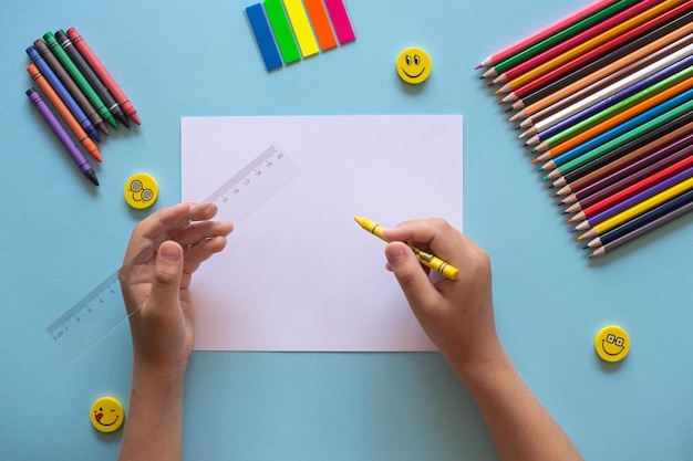 A set of bright stationery on a blue background. Hands holding a ruler