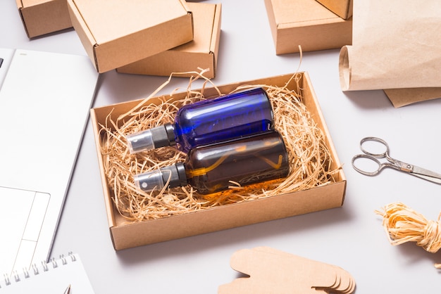 Set of brown and blue glass spray bottles packed in cardboard box on office desk