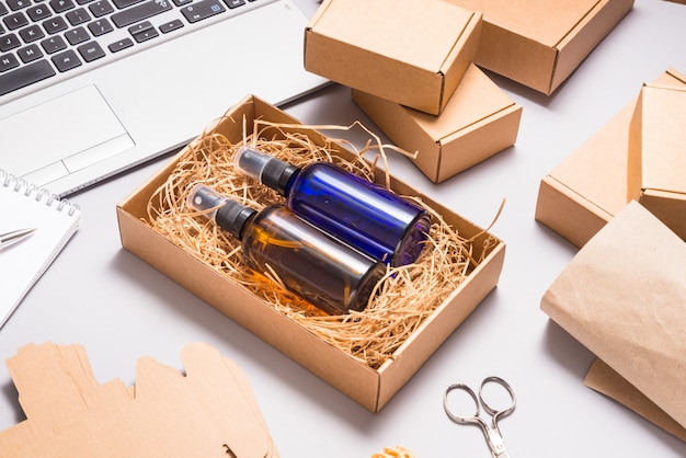 Set of brown and blue glass spray bottles packed in cardboard box on office desk