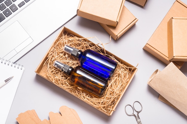 Set of brown and blue glass spray bottles packed in cardboard box on office desk