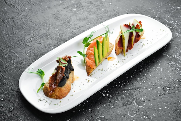 Photo a set of bruschetta with avocado tomatoes and meat antipasto cold snacks restaurant menu on a white plate