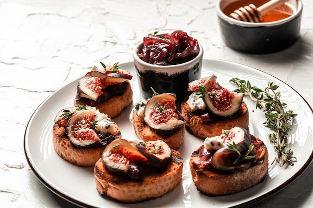 Set bruschettas with figs and goat cheese blue cheese and nuts\
onion jam fresh thyme honey on grilled crusty bread tasty appetizer\
wine banner catering menu recipe