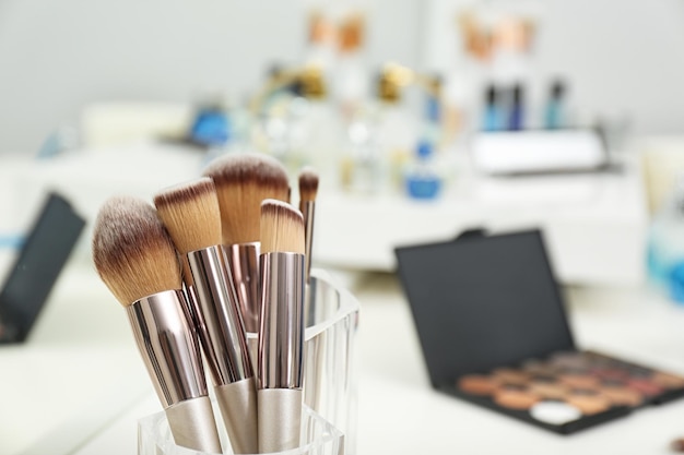 Set of brushes and other makeup products on white dressing table