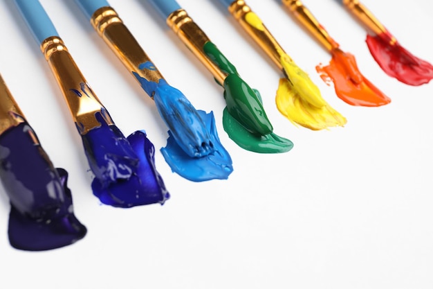 Set of brushes with different paints on white background closeup Rainbow colors