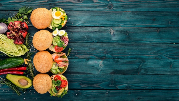 Set Burger sandwich with quail eggs cucumbers and corn salami and seafood On a wooden background Top view Copy space