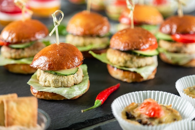 Set of burgers on black board on wooden table