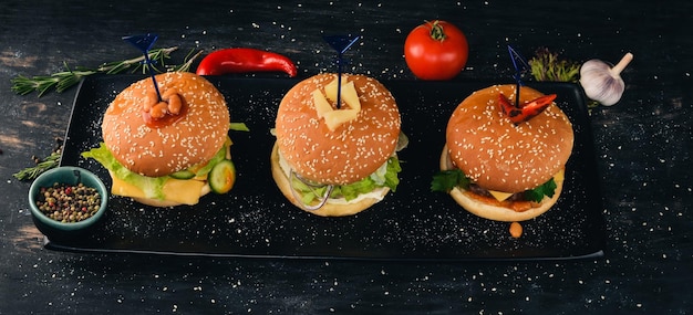 Set burgers with fish, meat, and vegetables. Top view. Free space for your text. On a wooden background.