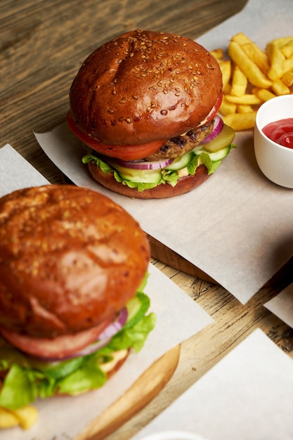 Set of burgers with french fries and ketchup sauce. Big hamburgers and french fries on wooden table background. Fast food set background. Restaurant burger menu