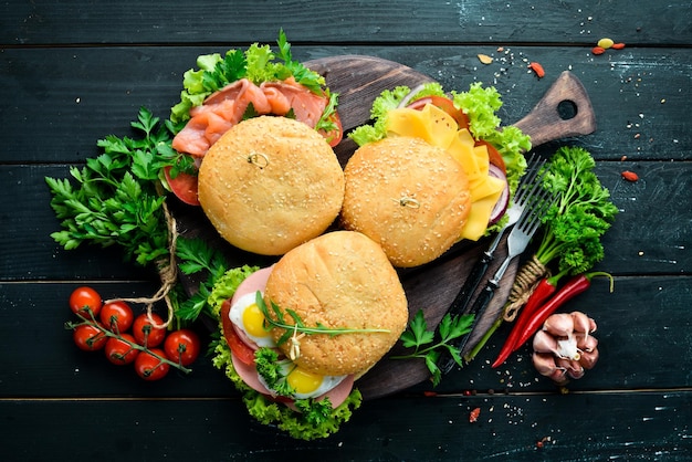 Set of burgers with meat cheese fish and vegetables On a black background Top view Free space for your text