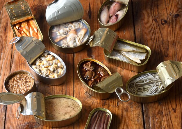 set of cans with fish and seafood on wooden background
