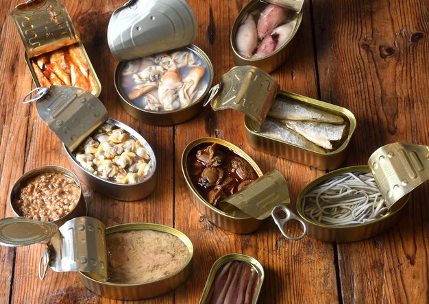 Set of cans with fish and seafood on wooden background