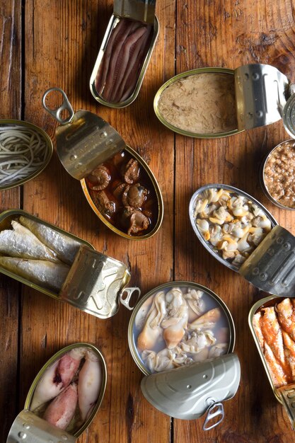 set of cans with fish and seafood on wooden background