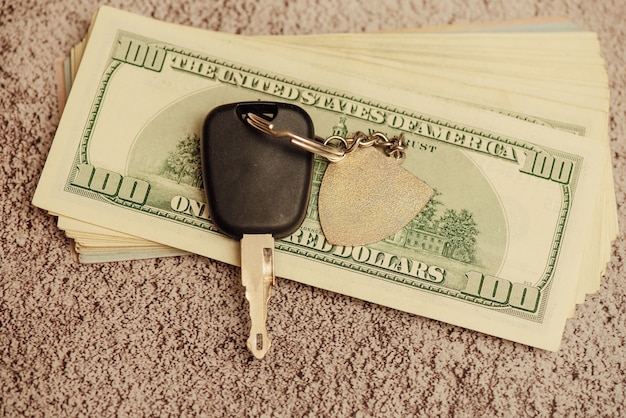 A set of car keys with cash, car payment. car keys and dollars.\
key from the car and money