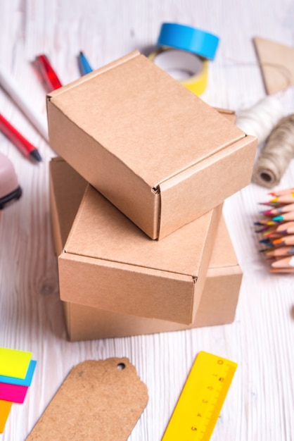 Set of cardboard boxes and stationery on wooden background, top view