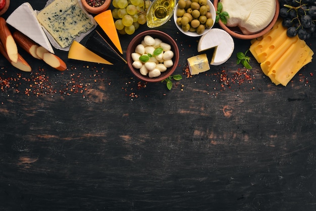 Set cheeses Suluguni blue cheese mozzarella maasdam brie cheese Top view On a black wooden background Free copy space